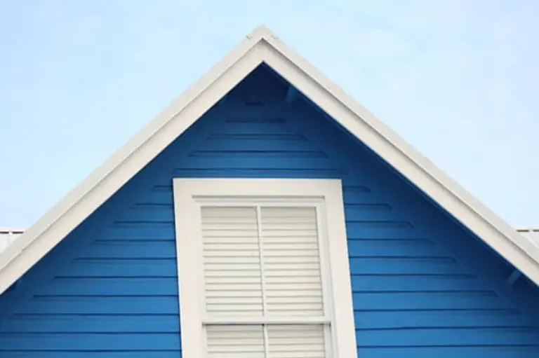 Freshly painted blue siding and white trim on a house gable